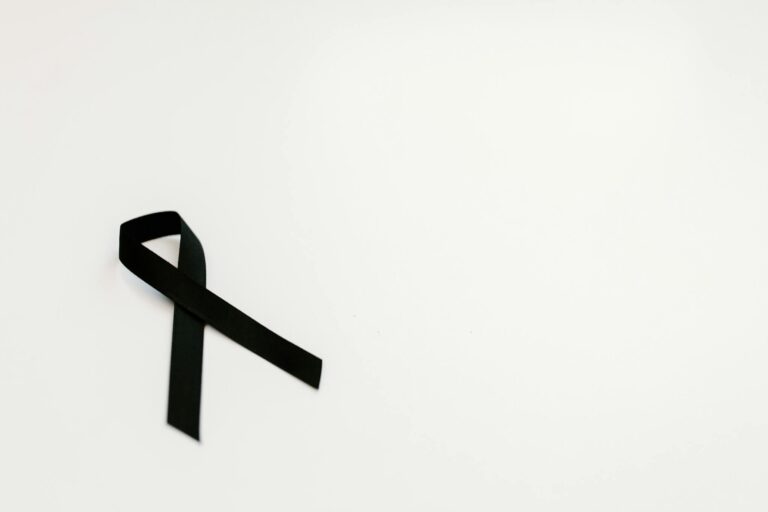 A black ribbon on a white background symbolizing mourning and remembrance, with ample copy space.