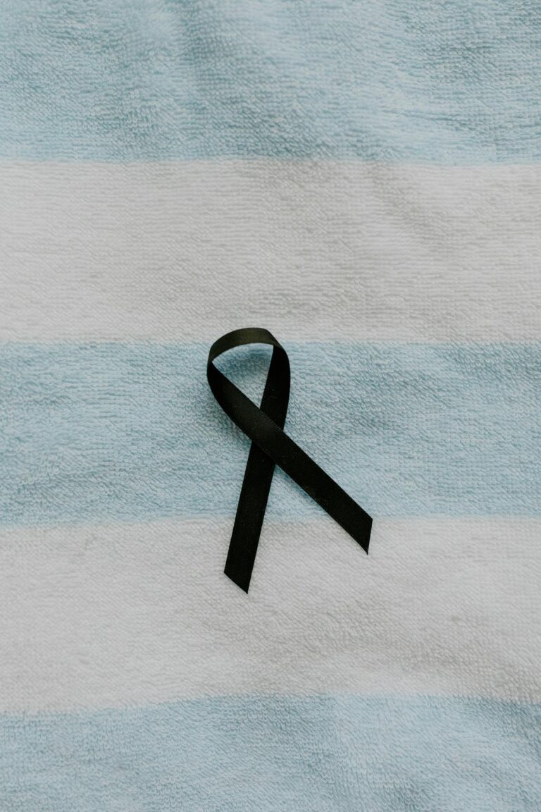 A black ribbon symbolizing mourning on a soft blue and white striped fabric background.