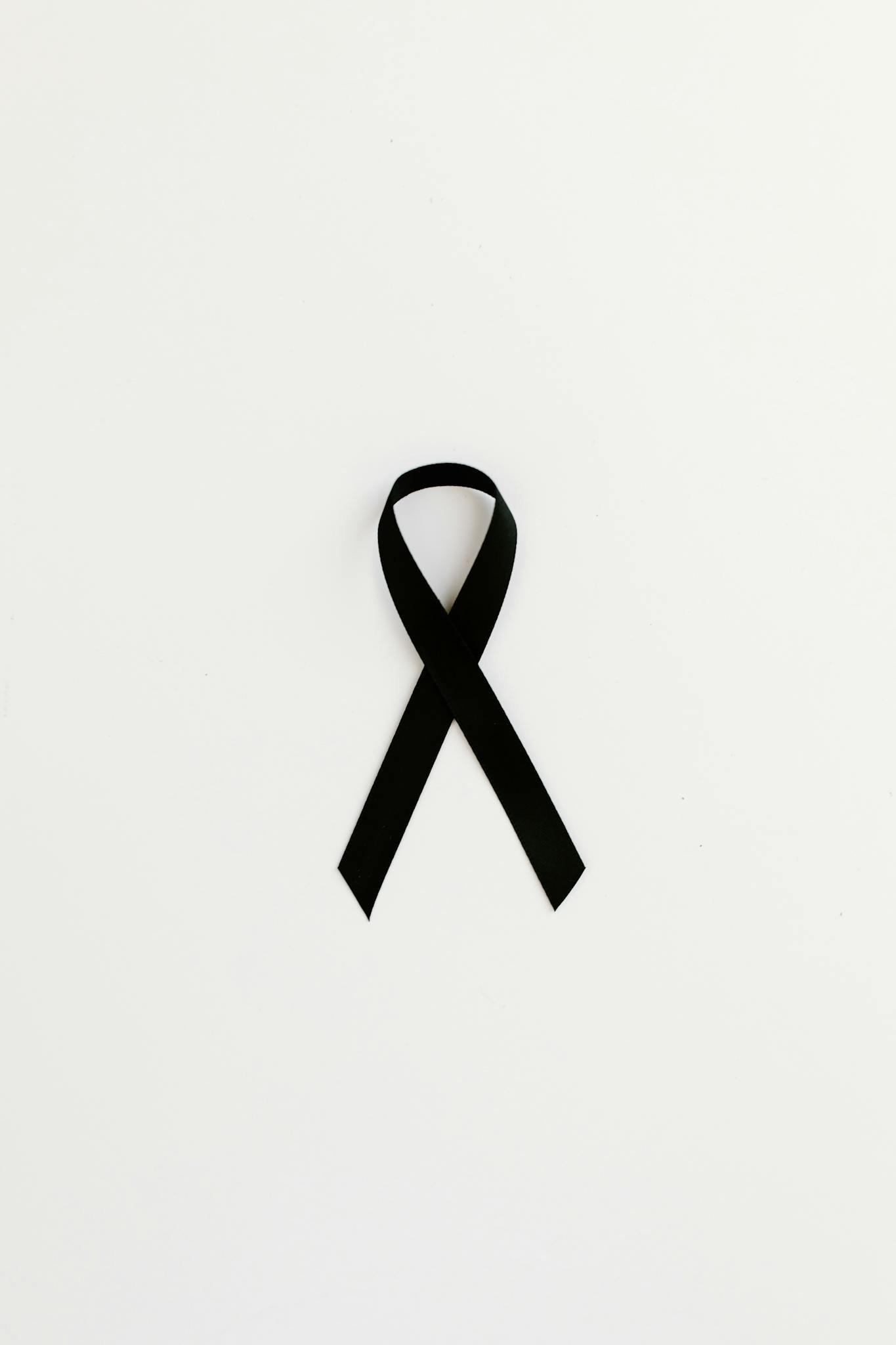 Minimalist black ribbon symbolizing cancer awareness on white background.